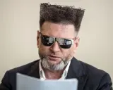 Detektyw Rutkowski is back! Z charakterystyczną fryzurą i okularami, czyta dokumenty.