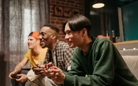Trzech przyjaciół gra w darmowe gry na PS4, śmiejąc się i rywalizując.