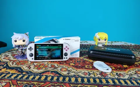 Biały handheld Trimui Smart Pro z grami, figurki Funko Pop i etui na konsolę.