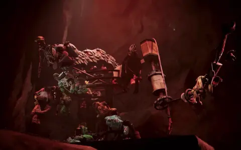Makabryczny prototyp Poppy Playtime: szkielety i potargane zabawki wiszą na metalowej konstrukcji w mrocznym, czerwonym świetle.