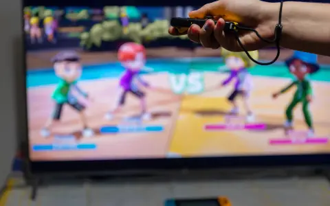 Ręka trzymająca kontroler do gry, na ekranie telewizora widać kolorowe postacie z gry ruchowej Nintendo Switch.