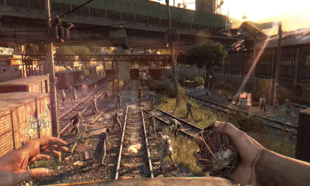 Gracz trzyma granat, otoczony przez hordę zombie na torach kolejowych. To scena z gry Dying Light, gdzie wymagania sprzętowe są kluczowe dla płynności rozgrywki.
