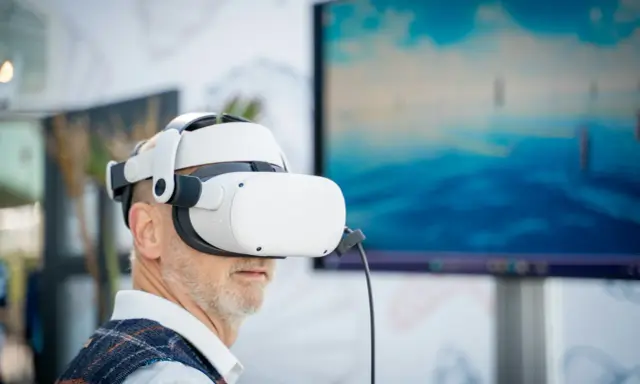 Mężczyzna w goglach VR zanurza się w wirtualnym świecie. Komputer do VR pozwala mu doświadczyć niesamowitych wrażeń.