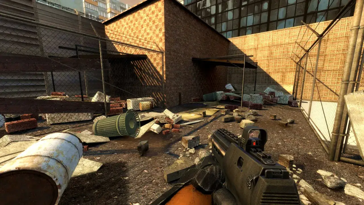 Zniszczony dziedziniec w Half-Life 2 Remastered. W ręku broń, wokół gruzy, beczki i zniszczone ogrodzenie.