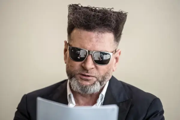 Detektyw Rutkowski is back! Z charakterystyczną fryzurą i okularami, czyta dokumenty.